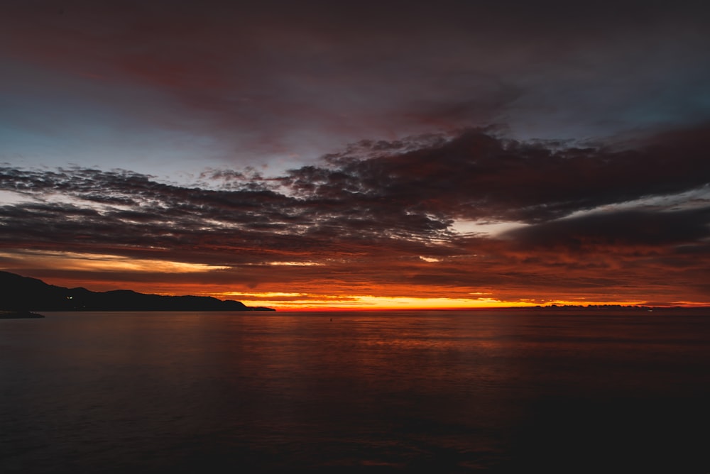 a sunset over a body of water with mountains in the background