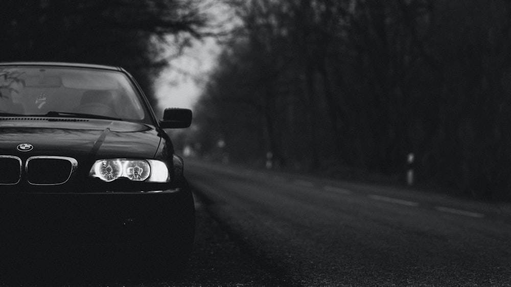 a black and white photo of a car parked on the side of the road