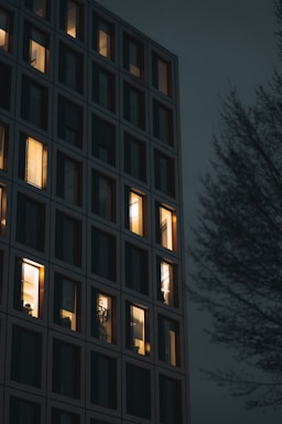 Evening shot of a multifamily building with lit windows.
