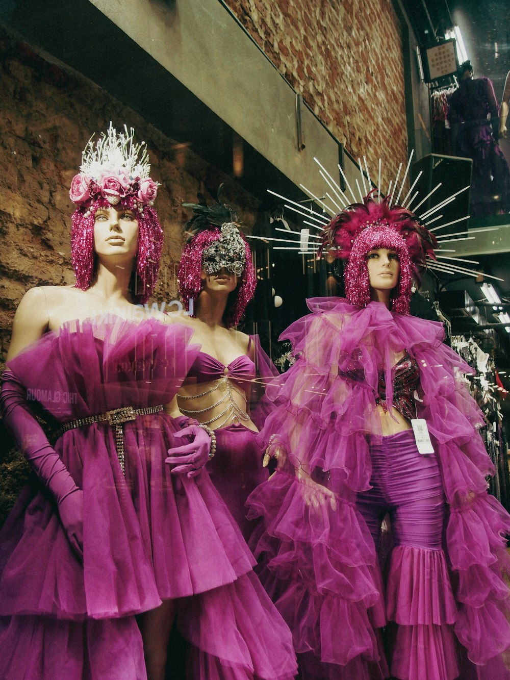 three mannequins dressed in purple dresses and headpieces