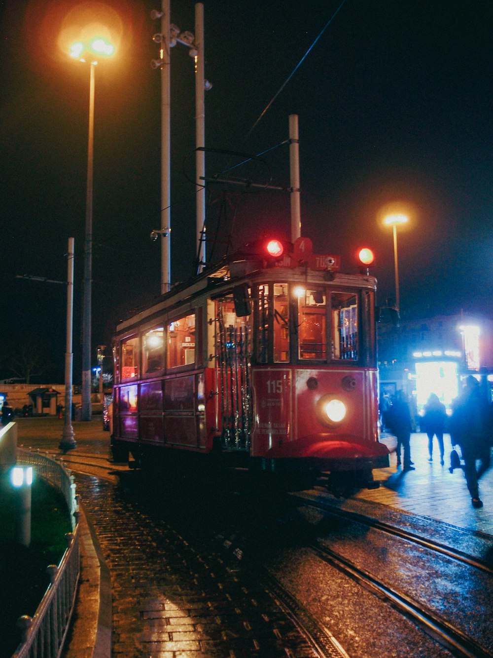 a red trolley car traveling down a street at night