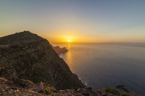 A stunning aerial shot of a coastal cliff at sunset with warm golden light.
