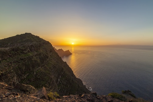 A sweeping aerial shot of a coastal cliff bathed in golden sunset light.