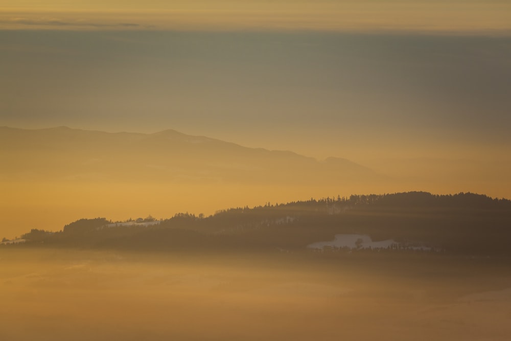 a foggy landscape with a mountain in the distance