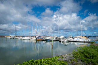 A serene marina under a clear blue sky with yachts docked and a visible map overlay highlighting port locations.