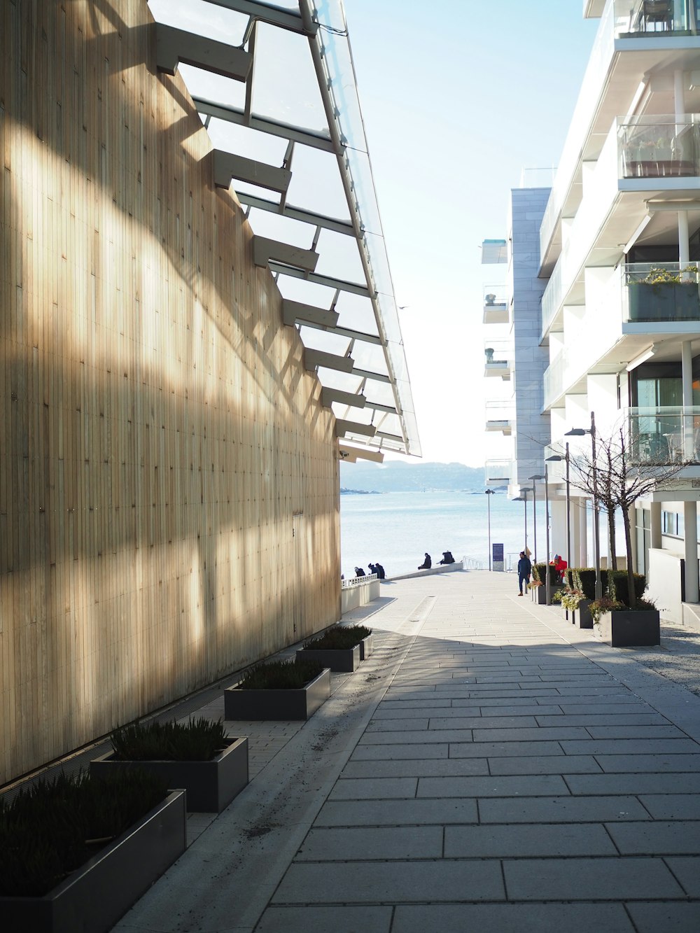 a walkway between two buildings with a view of a body of water