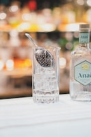 A chilled gin bottle surrounded by fresh botanicals and ice cubes on a rustic wooden table