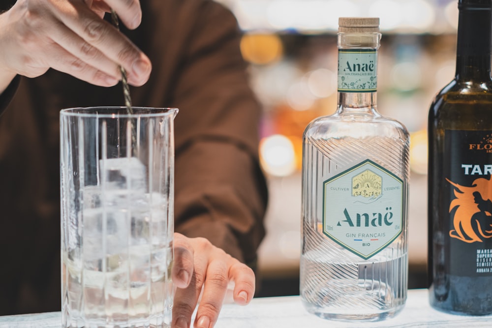 a person sitting at a table with two bottles of alcohol