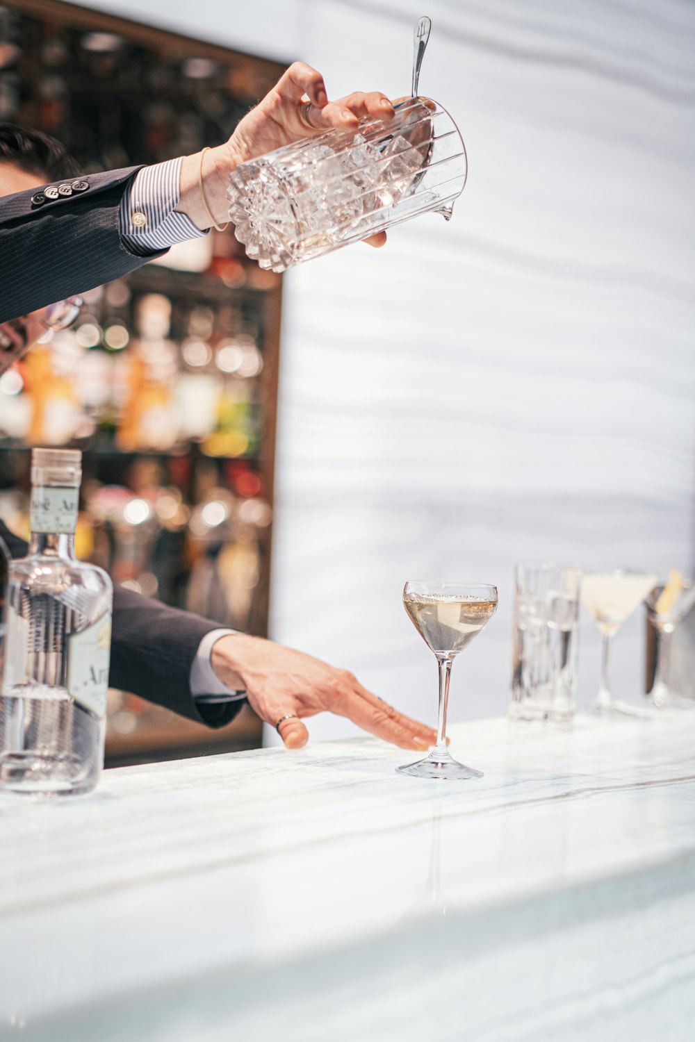 a bartender pouring a martini into a glass