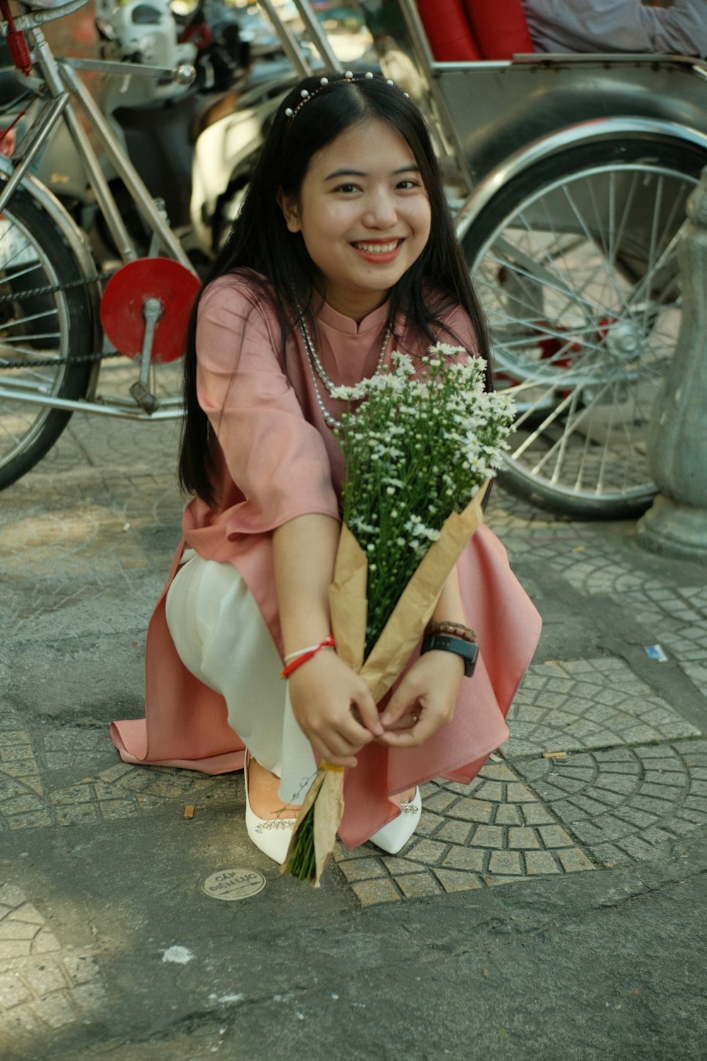 a woman kneeling down holding a bouquet of flowers