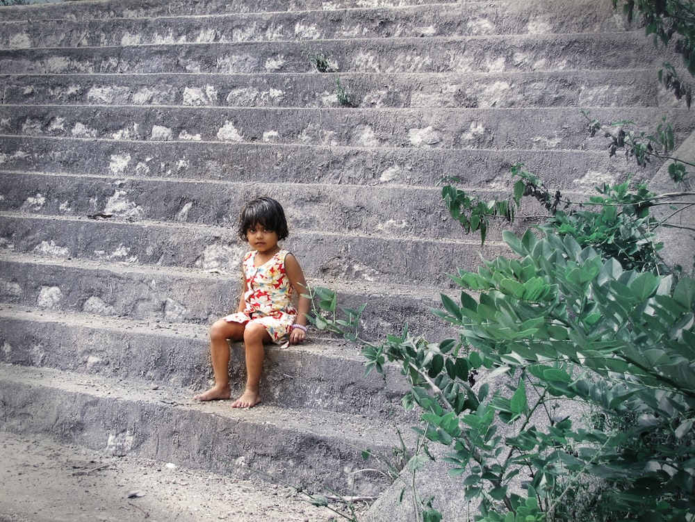 a little girl sitting on a set of stairs