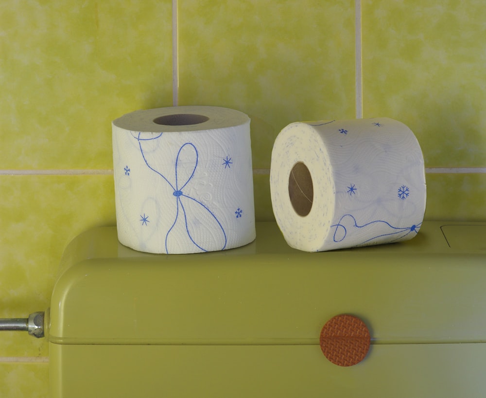 two rolls of toilet paper sitting on top of a green cabinet