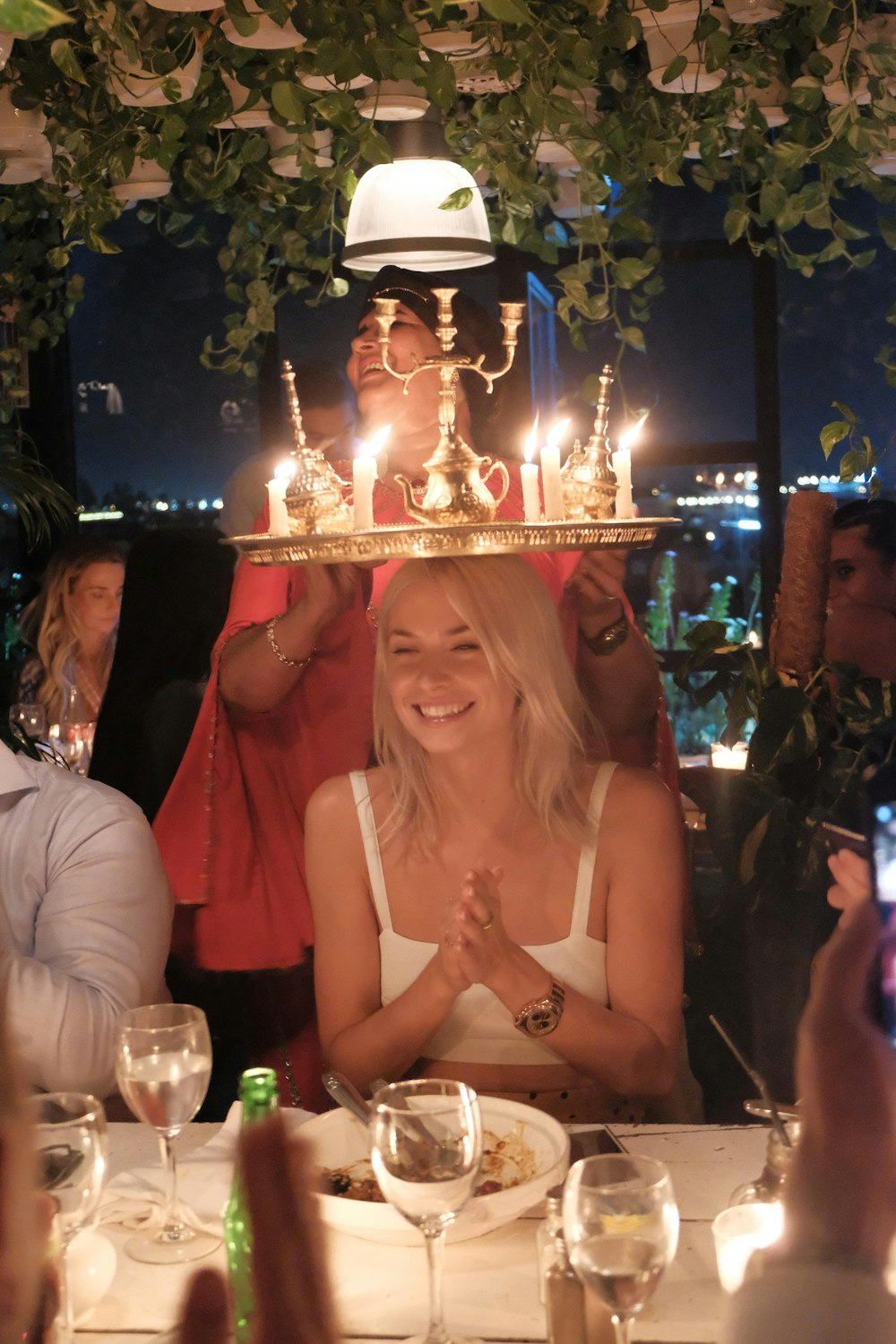 Una mujer sentada en una mesa con un pastel encima de su cabeza