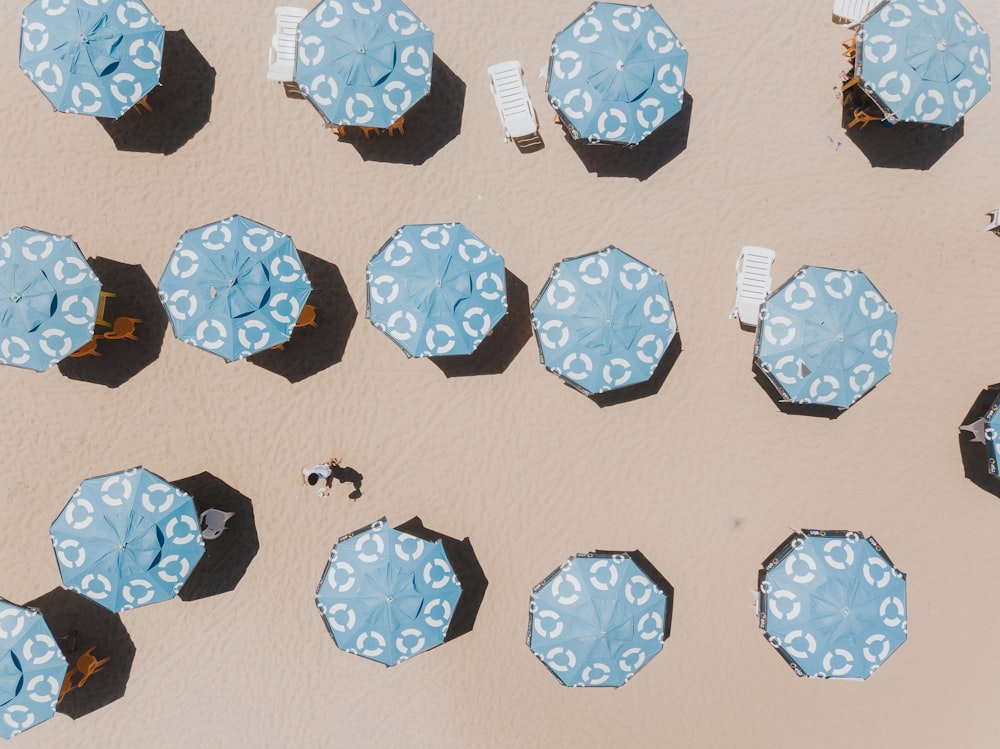 a group of blue umbrellas sitting on top of a sandy beach