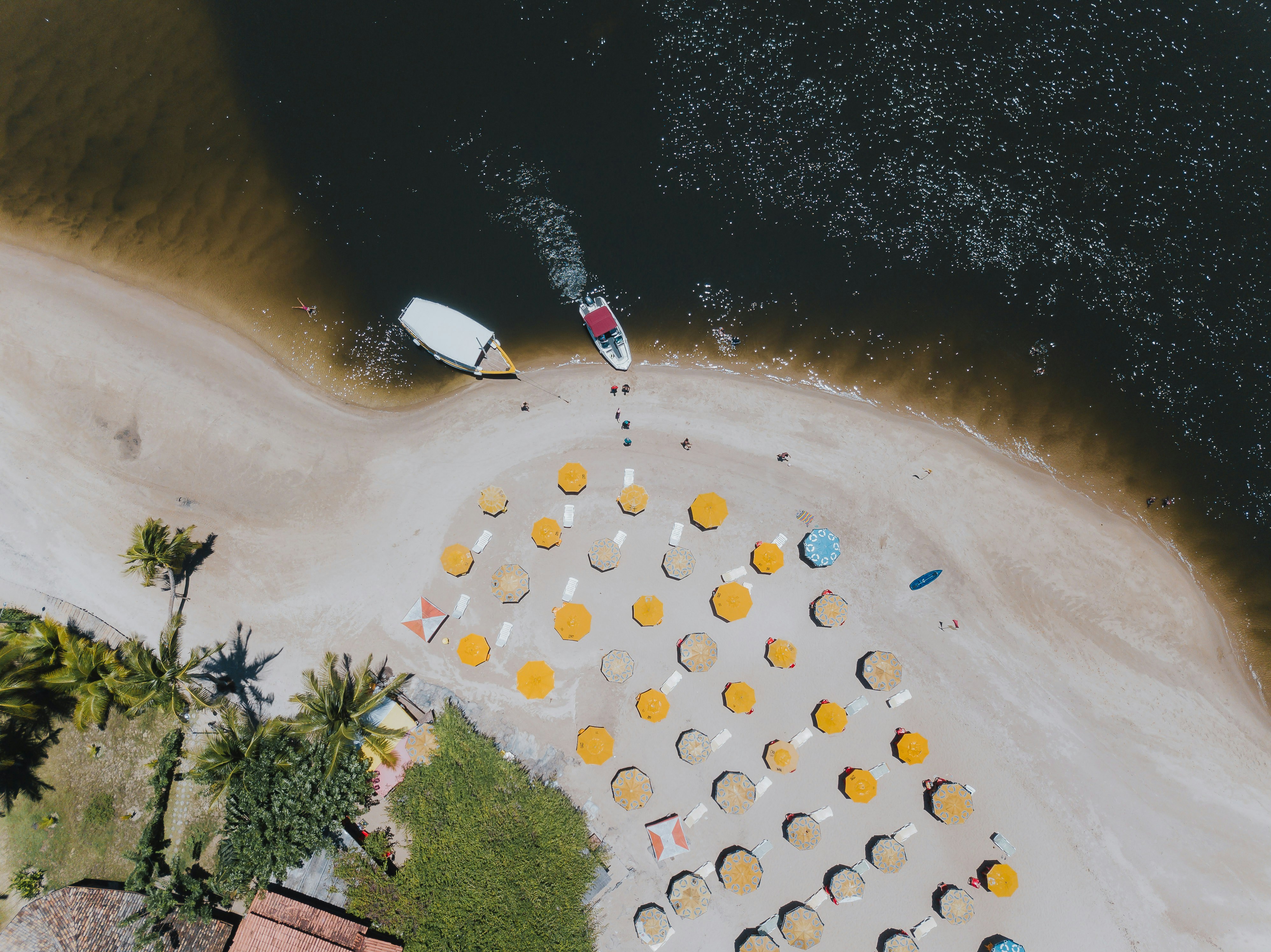 an aerial view of a beach with umbrellas and chairs