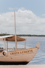 a boat sitting on top of a beach next to a body of water