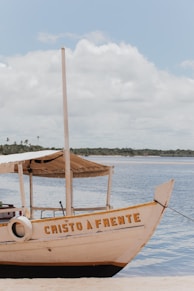 a boat sitting on top of a beach next to a body of water