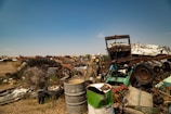 A wide view of the scrapyard showing various metal scraps under sunlight.