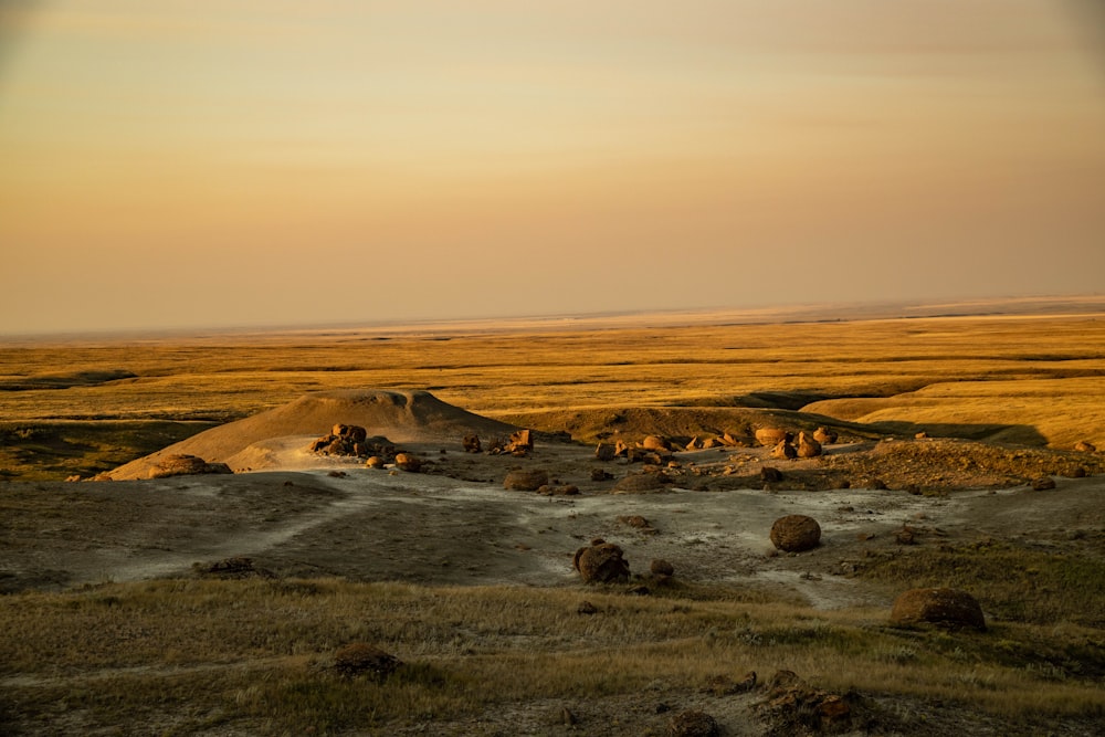 a large open field with a dirt hill in the distance