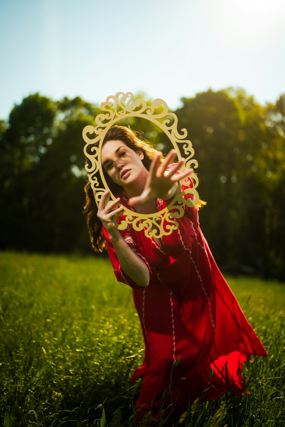 a woman in a red dress is holding a mirror