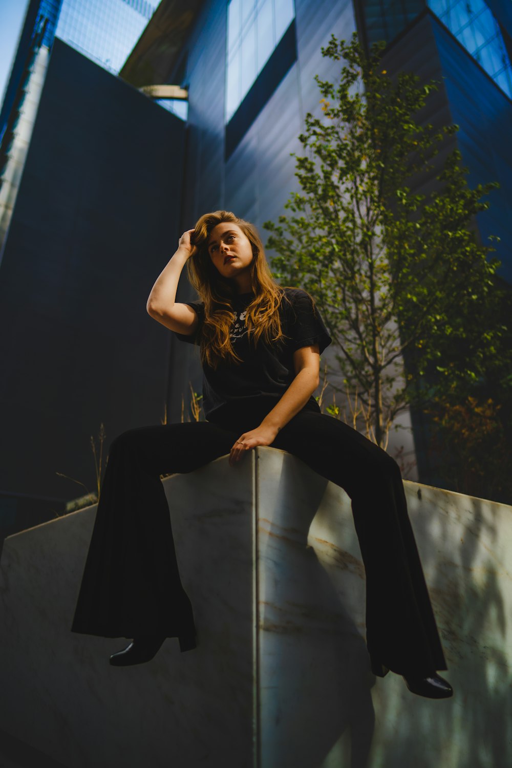 a woman sitting on top of a cement wall