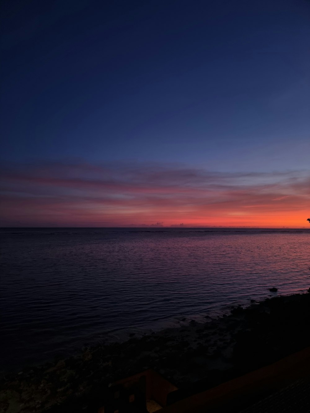 the sun is setting over the ocean with a lighthouse in the foreground