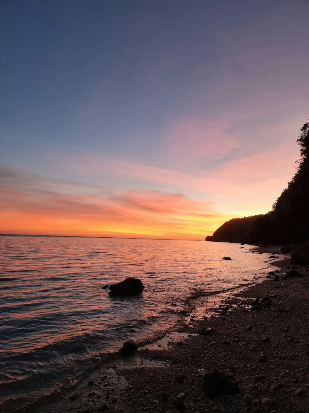 the sun is setting over the water at the beach