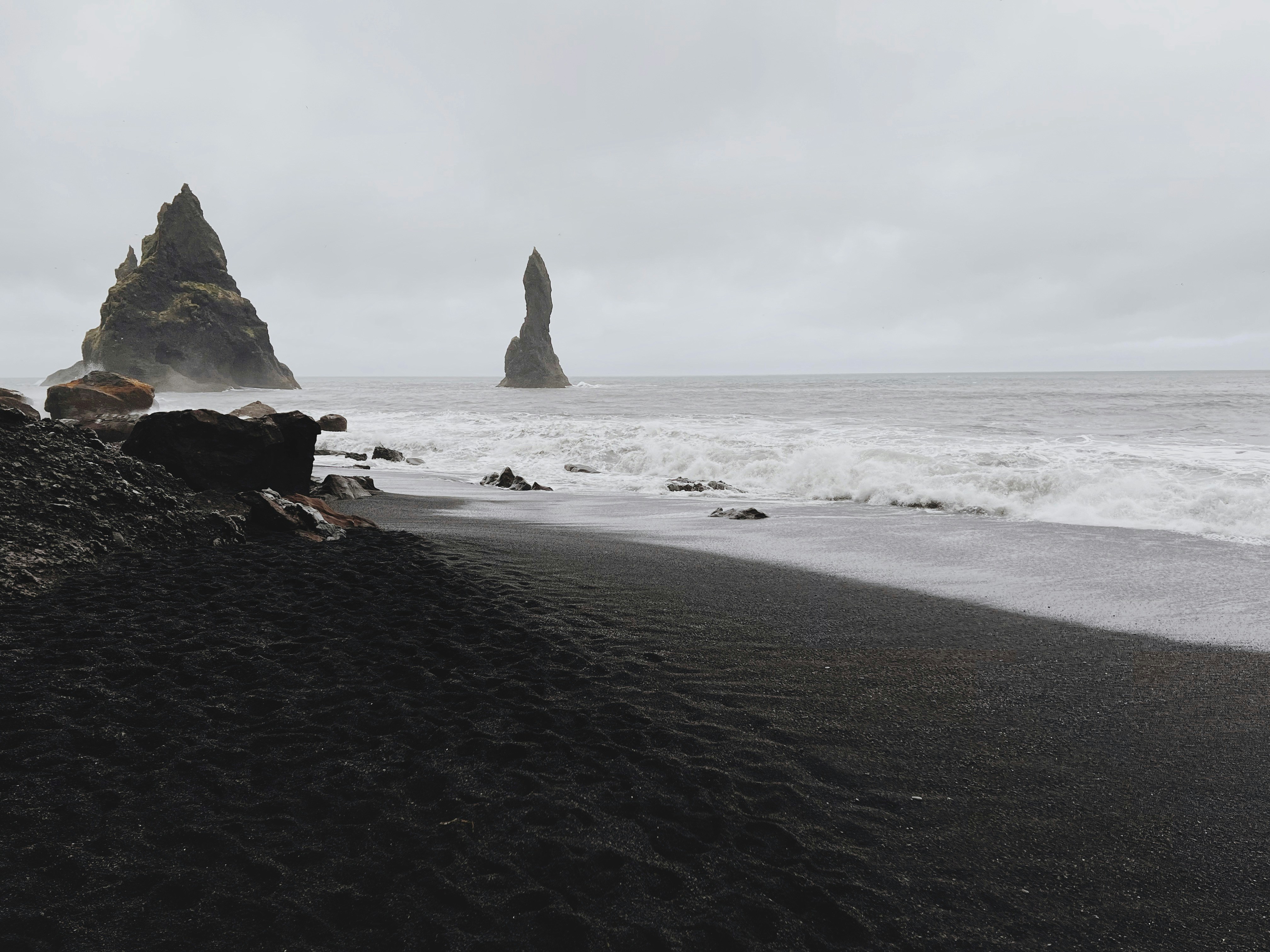 a black sand beach with a rock formation in the background