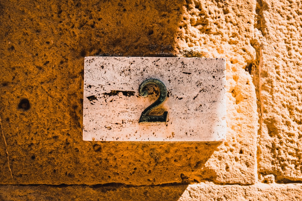 a number two sign on a stone wall