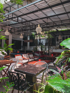 Outdoor patio area with comfortable seating, surrounded by lush greenery and ambient lighting.