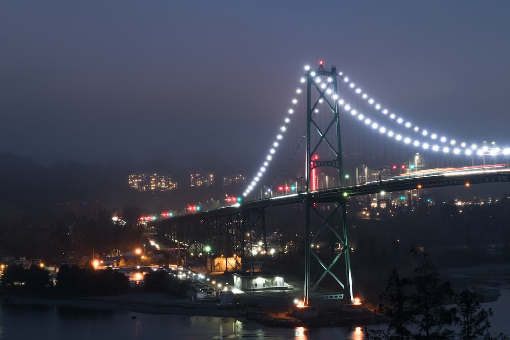 a large bridge with lights on it over a body of water