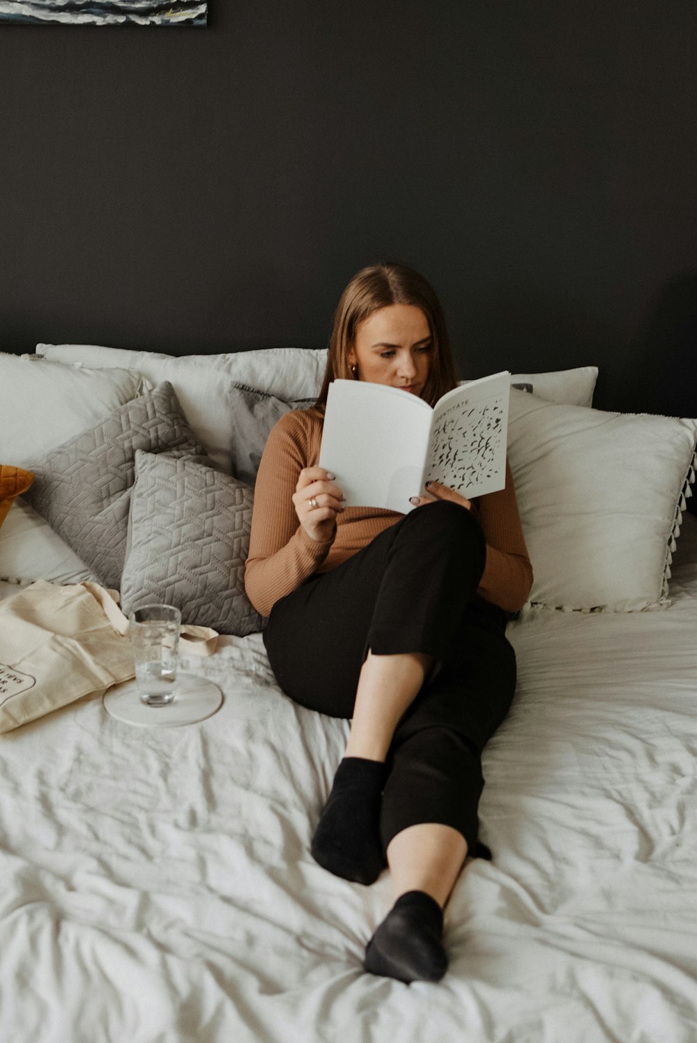 a woman sitting on a bed reading a book