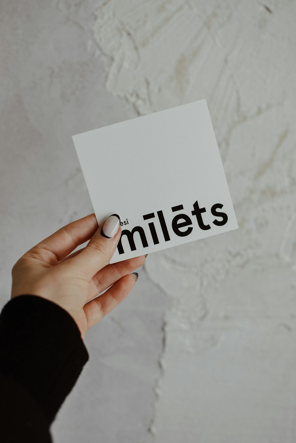 a person holding a piece of paper with the word miles printed on it