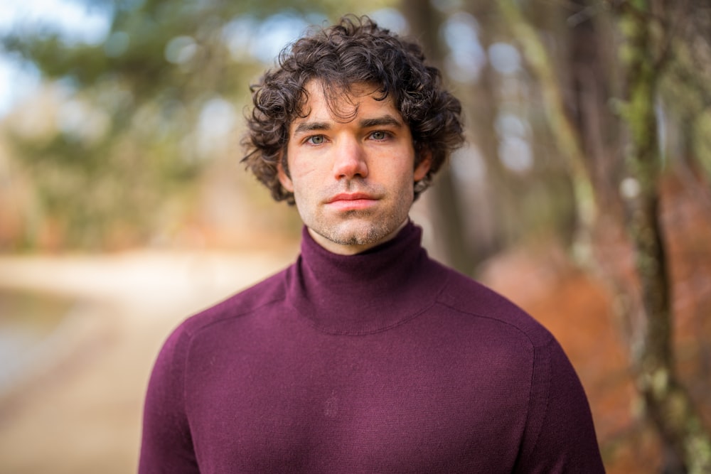 a man with curly hair wearing a turtle neck sweater