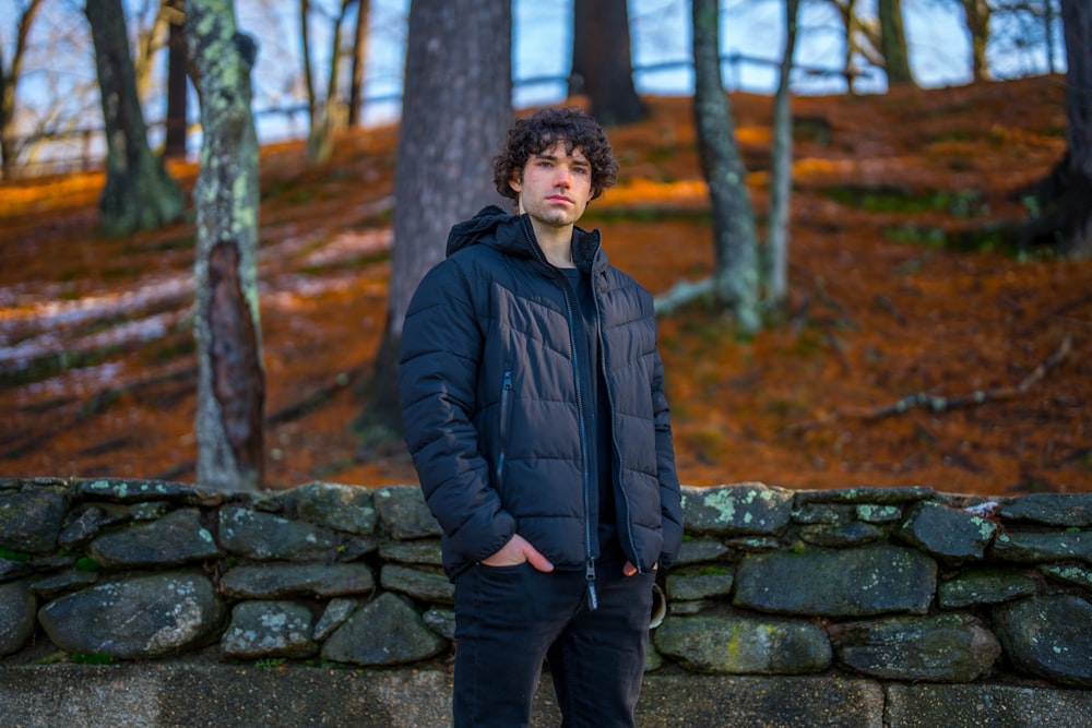 a man standing in front of a stone wall