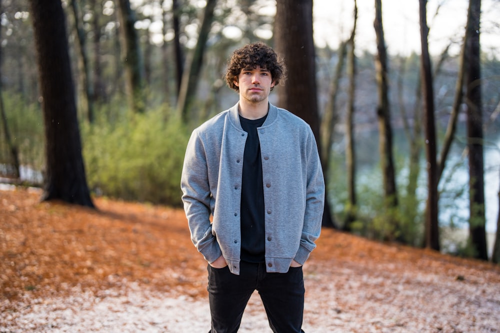 a young man standing in a wooded area