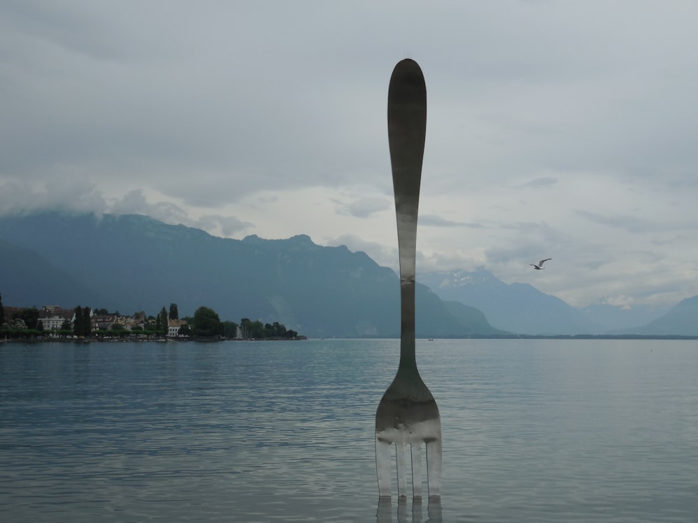 a fork sticking out of the water with mountains in the background