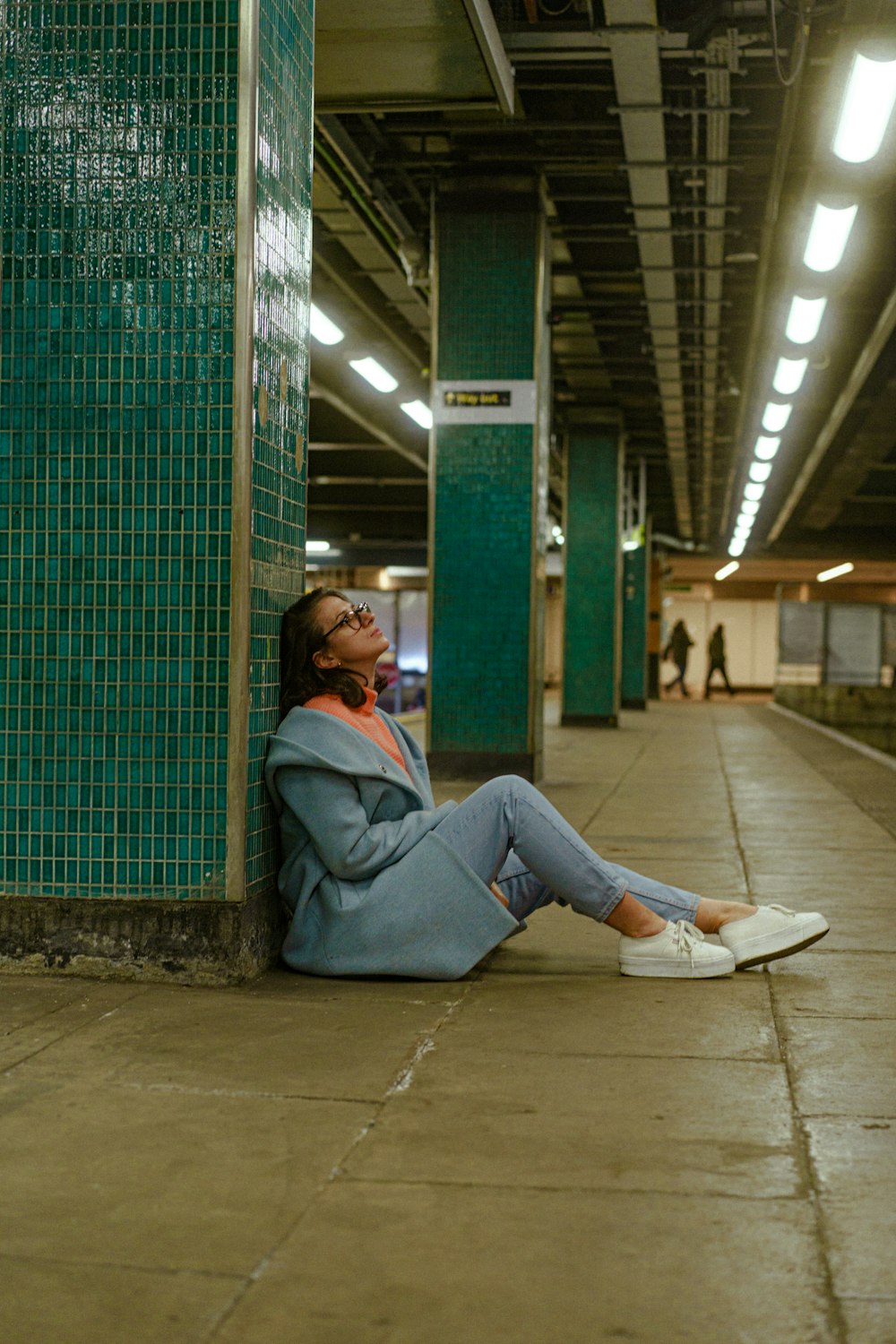 a woman sitting on the ground in a subway station