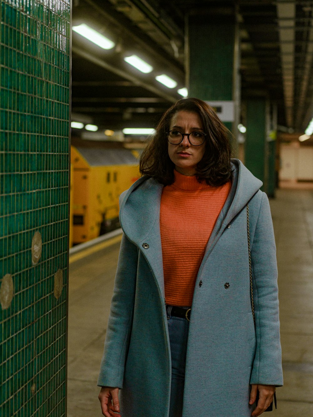 a woman standing next to a green tiled wall