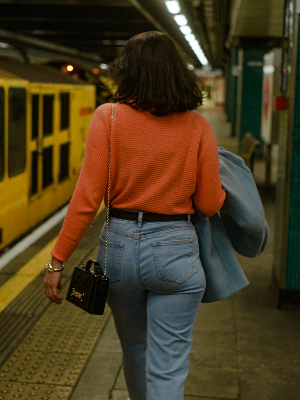 a woman is walking towards a train at a station