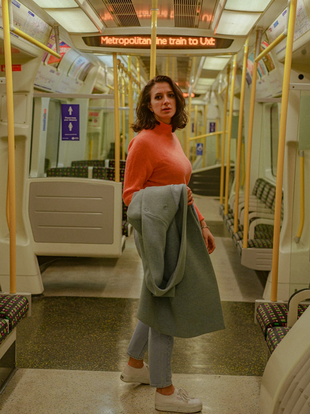 a woman standing on a subway train with her hand in her pocket