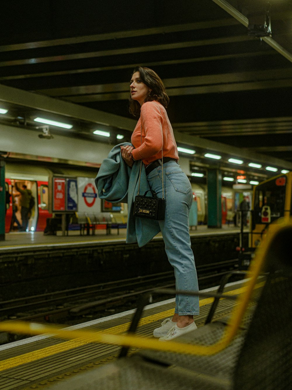 a woman standing on a train platform with her back to the camera