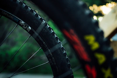 Close-up of mountain bike tires gripping a dirt trail with mountain peaks in the background.