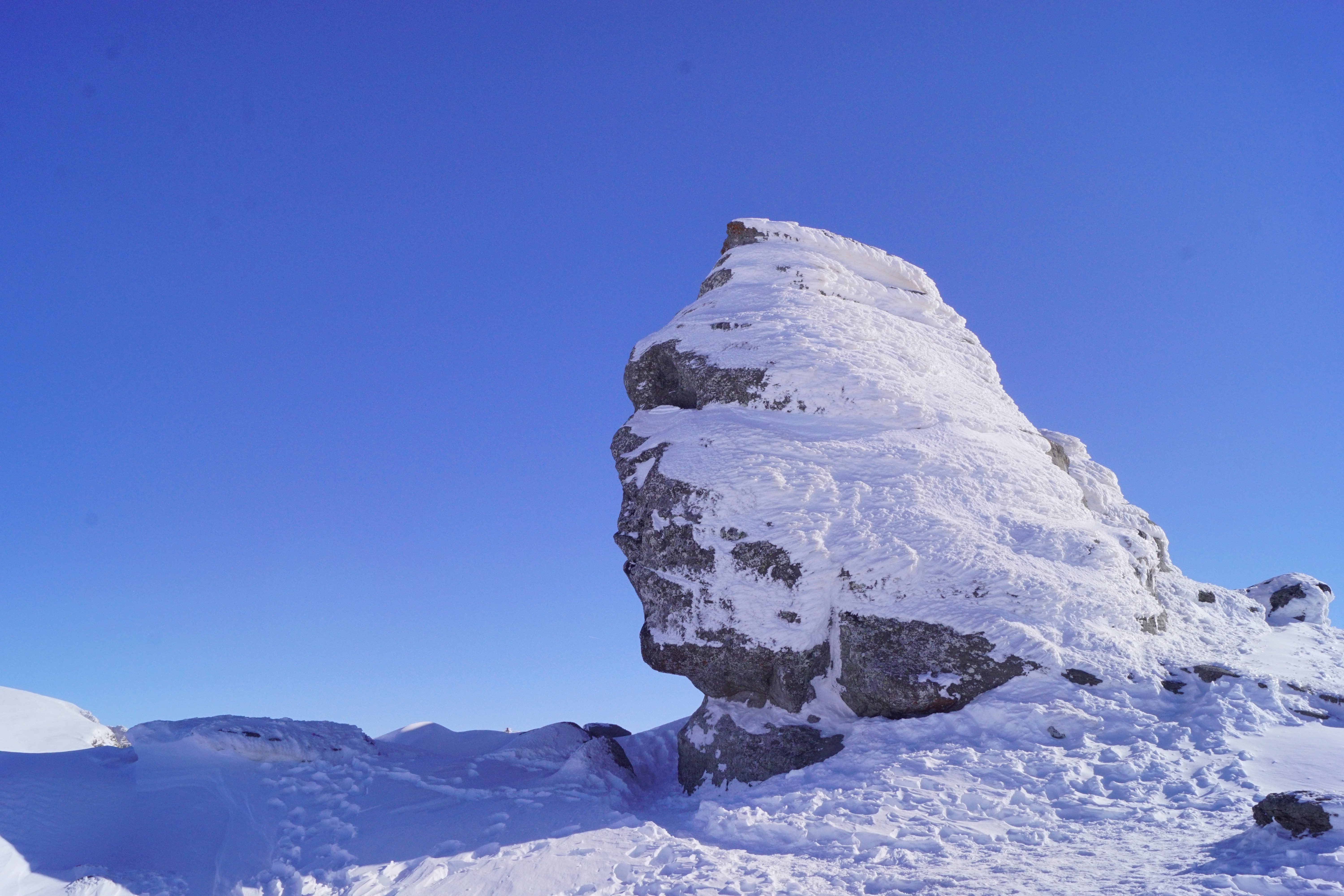 A large rock in the middle of a snowy field