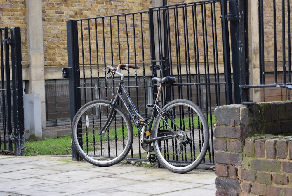 a bicycle locked to a fence on a sidewalk