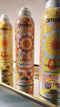Close-up of sleek, modern body spray cans arranged on a dark metallic surface.