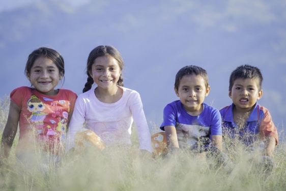 Four kids happily working together in a sunny yard, pulling weeds and tidying up.