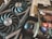 A close-up of a computer graphics card with two large cooling fans labeled ROG Strix, alongside a package of thermal paste labeled Conductonaut and a bottle of liquid cooling solution. The items appear to be for enhancing computer performance and cooling.