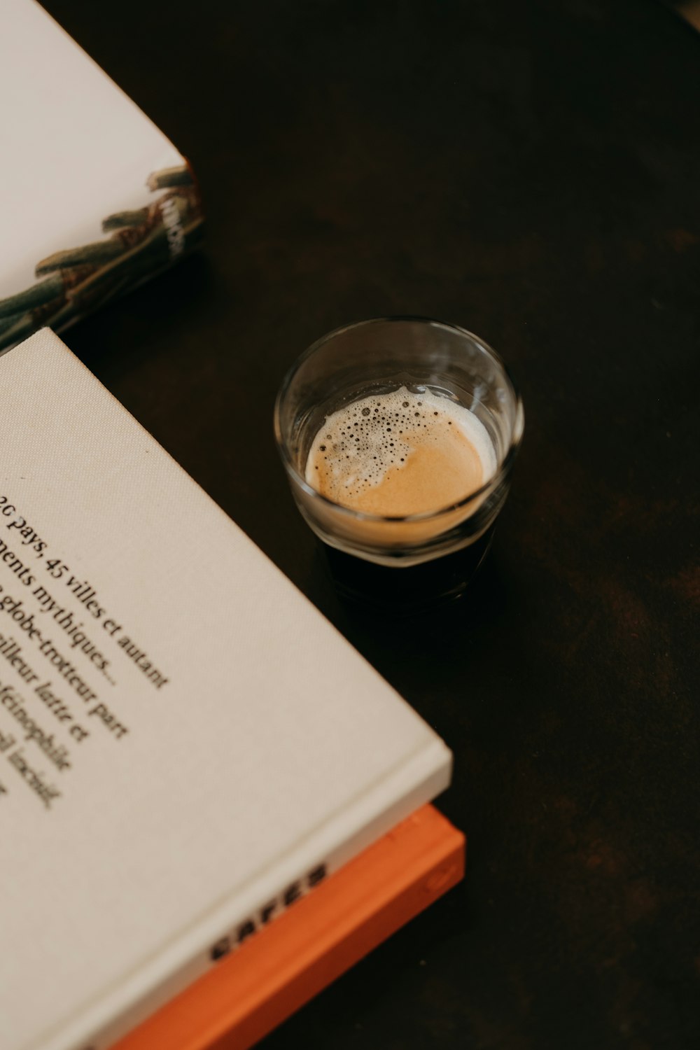 a cup of coffee sitting on top of a table next to a book