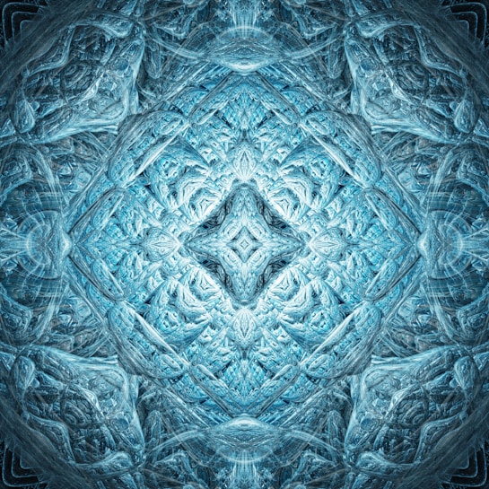 Intricate fractal patterns in hues of blue and white create a symmetrical, abstract design resembling ice or crystal formations. The central area features a diamond shape with layers radiating outward, giving a sense of depth and complexity.